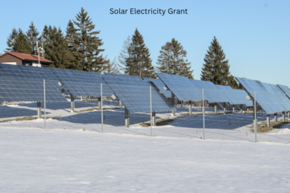 Ground mounted solar panels installed in a snowy field with the text Solar Electricity Grant under a clear blue sky.