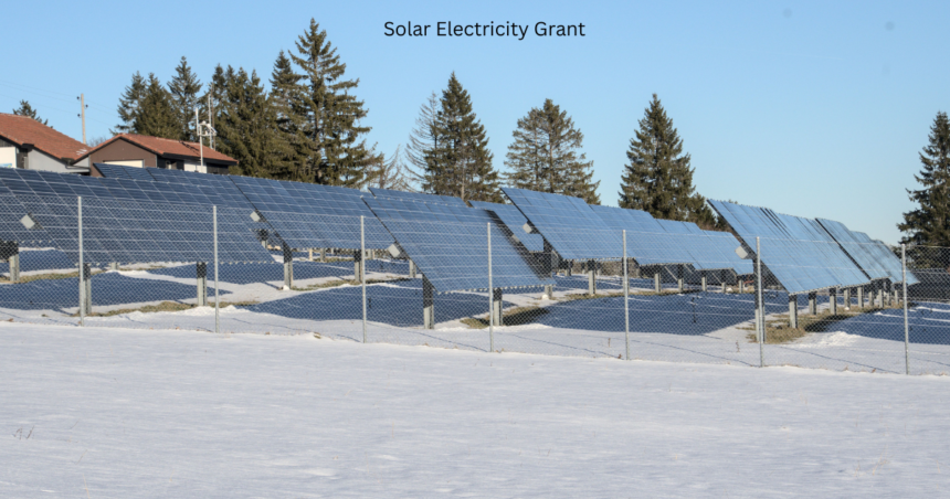 Ground mounted solar panels installed in a snowy field with the text Solar Electricity Grant under a clear blue sky.