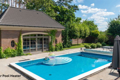 A backyard swimming pool with clear blue water next to a brick pool house, kept warm using a solar pool heater.