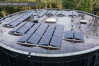 Aerial view of black solar panels for water pumps mounted on a large circular rooftop structure surrounded by green trees.