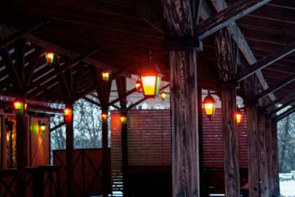 Solar lighting shed with warm outdoor lights illuminating a rustic wooden shelter in a snowy setting.
