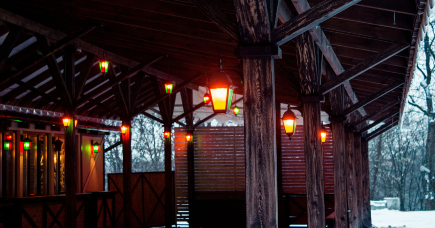 Solar lighting shed with warm outdoor lights illuminating a rustic wooden shelter in a snowy setting.
