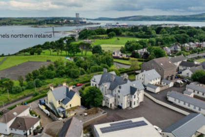 Solar panels Northern Ireland – aerial view of rooftop solar panel installation in a coastal town with harbor and green hills in background