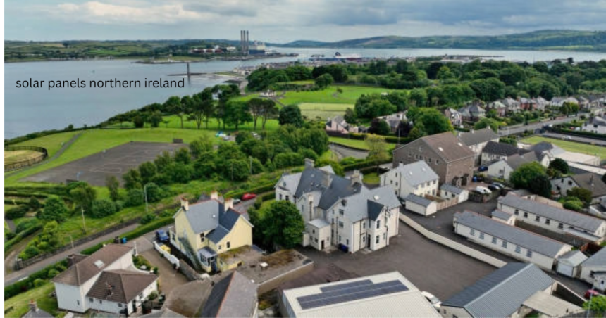 Solar panels Northern Ireland – aerial view of rooftop solar panel installation in a coastal town with harbor and green hills in background