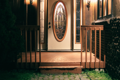 Warm motion sensor light outdoor illuminating a wooden house entrance and porch at night