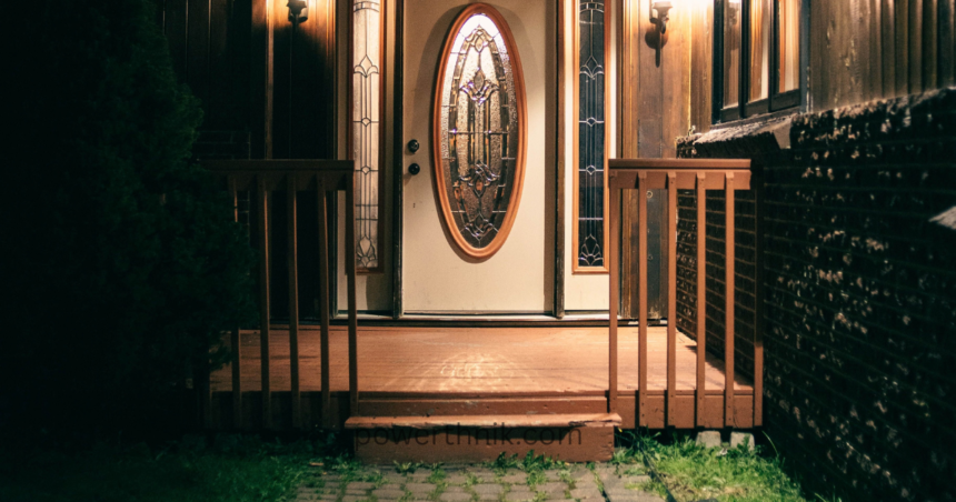 Warm motion sensor light outdoor illuminating a wooden house entrance and porch at night