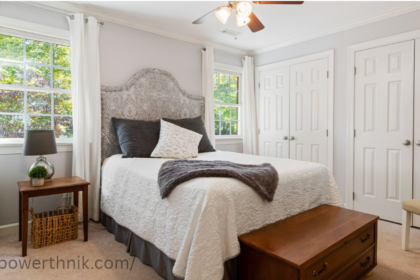 Ceiling fan light in a modern bedroom with white bedding and natural light.